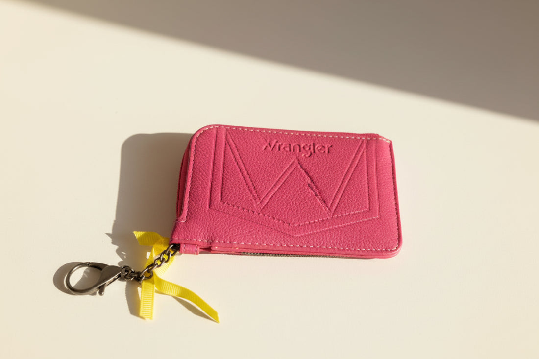 Pink wallet with a keychain on a beige background