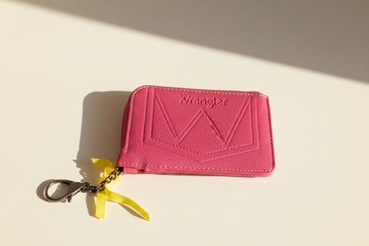 Pink wallet with a keychain on a beige background