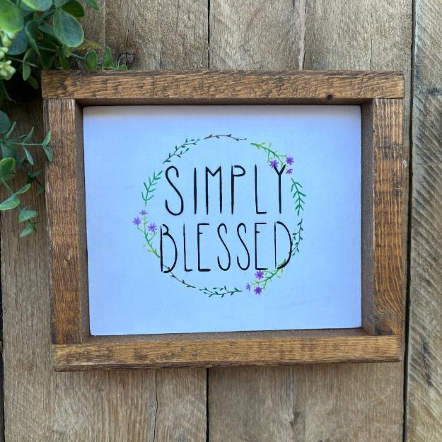 wood farmhouse framed sign that reads simply blessed on spring flower backgroud