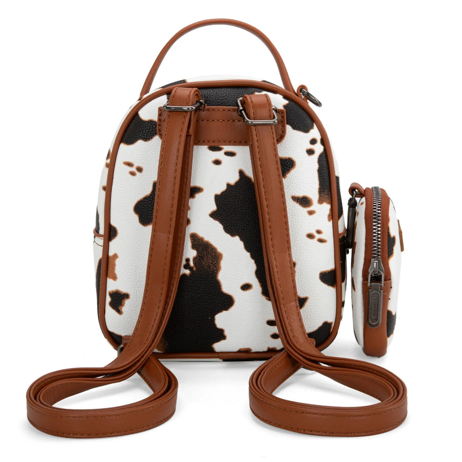 Cow print mini backpack with brown leather straps on a white background
