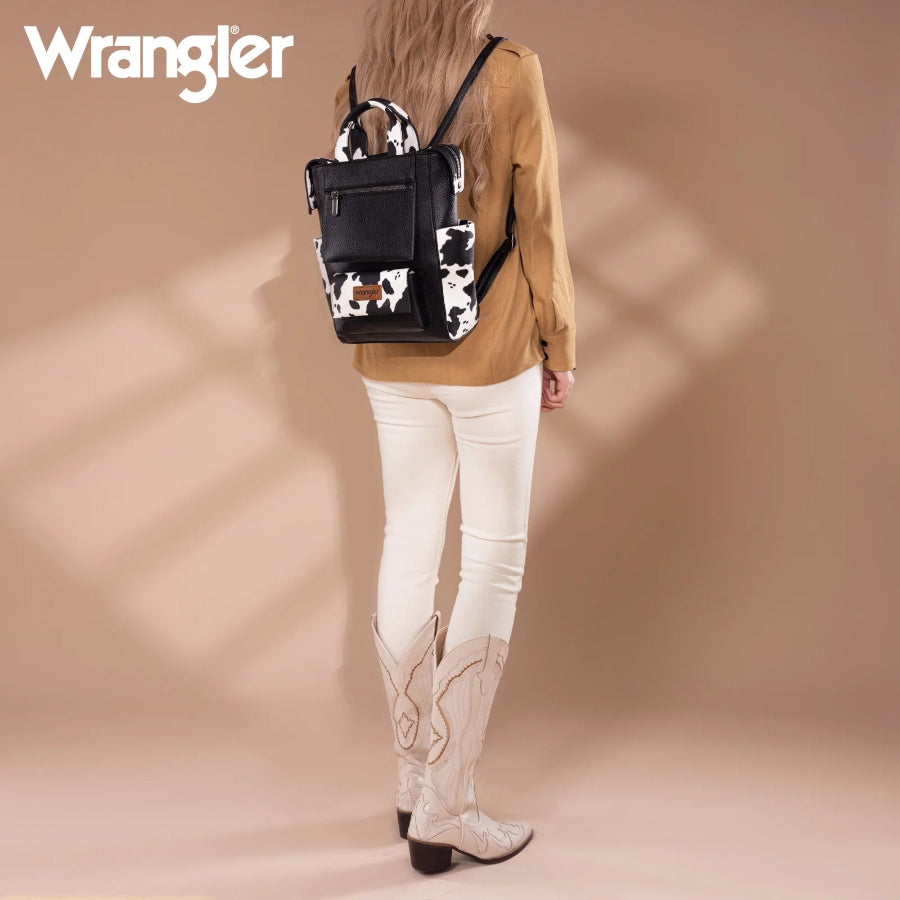 Person wearing a cow print backpack with a beige background, featuring the Wrangler brand.