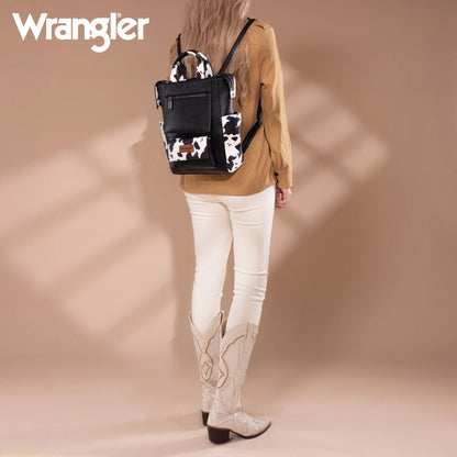 Person wearing a cow print backpack with a beige background, featuring the Wrangler brand.