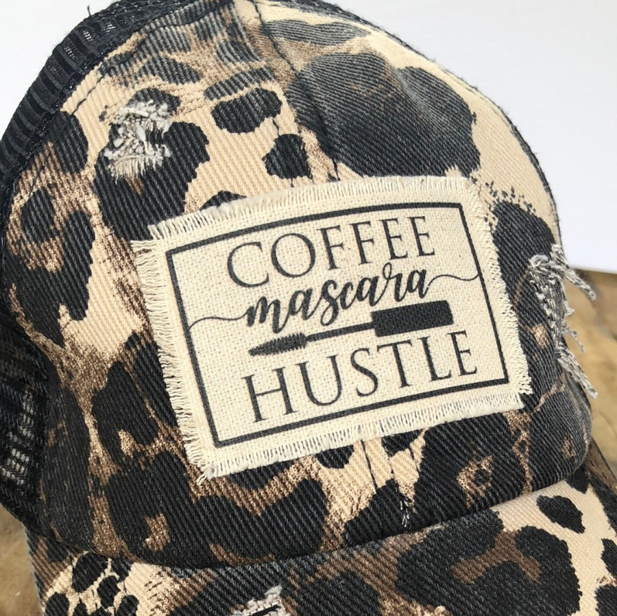 close up of distressed leopard baseball cap patch reads coffee mascara hustle