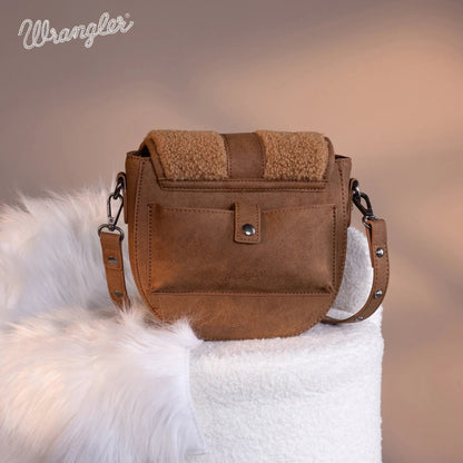 Brown leather handbag with fur trim on a white fur surface, featuring the Wrangler brand.