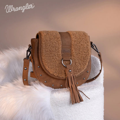 Brown textured handbag with tassel on a white fur surface, Wrangler brand visible.