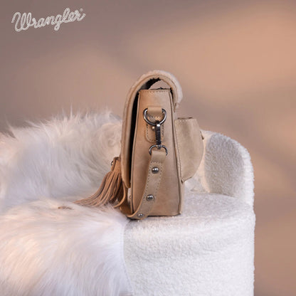 Beige handbag with tassel on a white furry surface, Wrangler logo visible