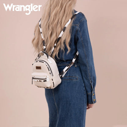 Person wearing a white backpack with cow pattern straps, standing against a beige background with 'Wrangler' branding.