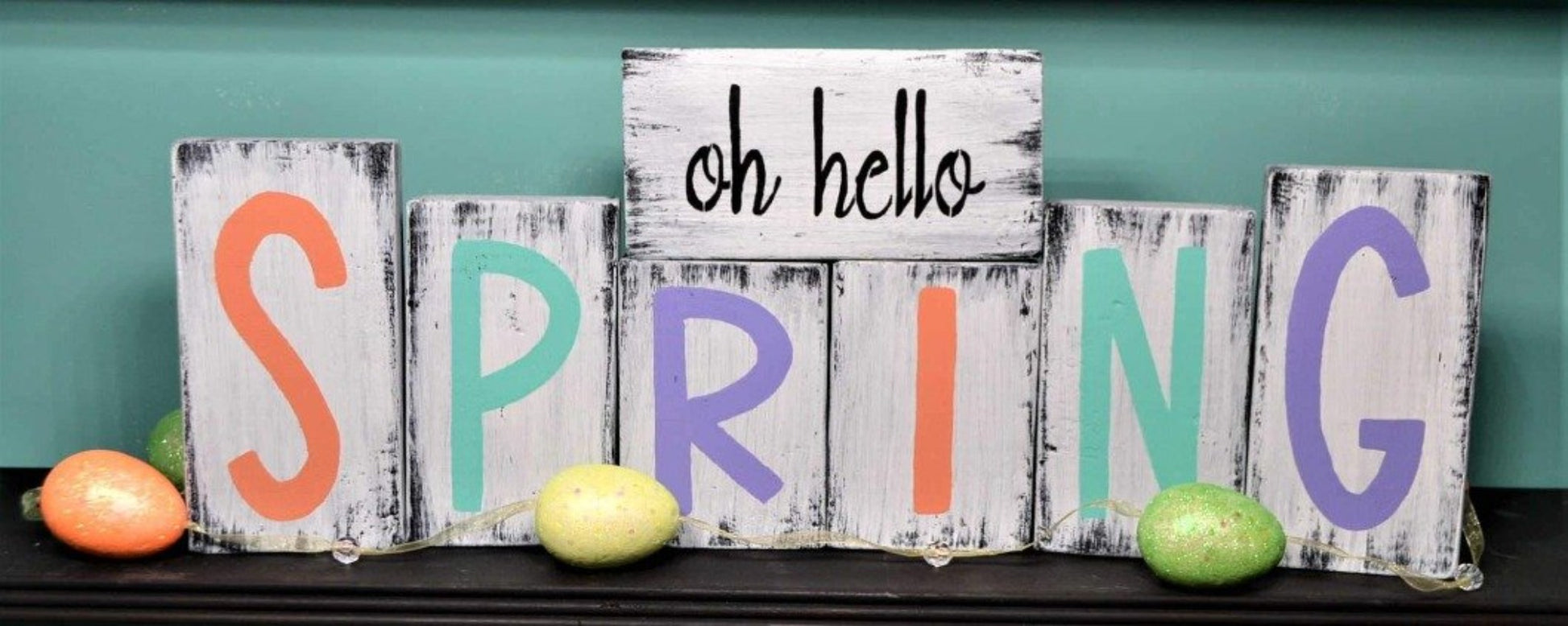 white distressed wood blocks that sit on a shelf. Hand painted Oh hello SPRING in fun spring colors  on distressed white block.